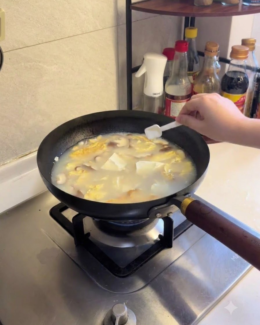 Salz und weißer Pfeffer werden in die köchelnde Tofu-Pilz-Suppe gestreut.