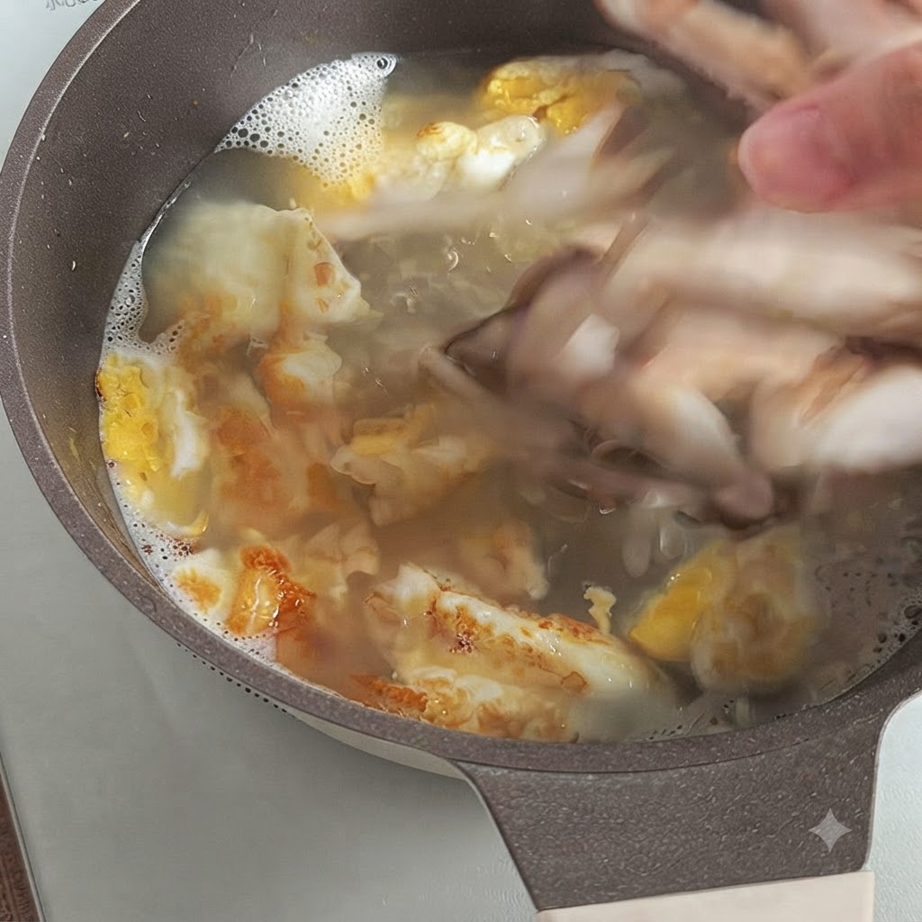 Eine Hand gibt geschnittene frische Shiitake-Pilze in eine kochende Brühe mit gebratenen Eierstücken.