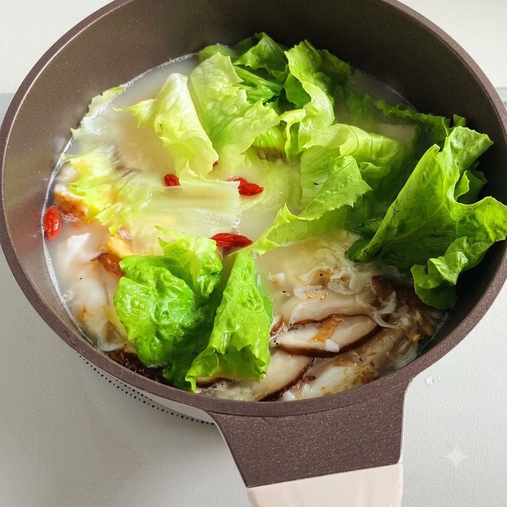 Ein Topf mit köchelnder Suppe mit Salatblättern und roten Goji-Beeren, die darin schwimmen.