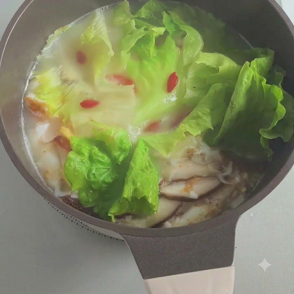 Gehackte Frühlingszwiebeln werden in den köchelnden Suppentopf gestreut.