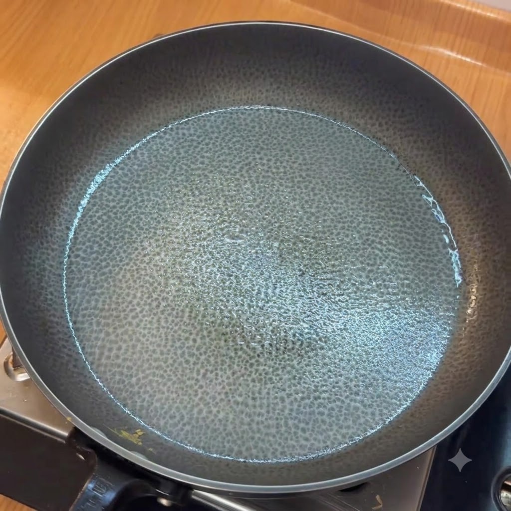 Gehackter Knoblauch wird in einer gefetteten Pfanne angebraten, bevor gehackte Tomaten hinzugefügt werden.