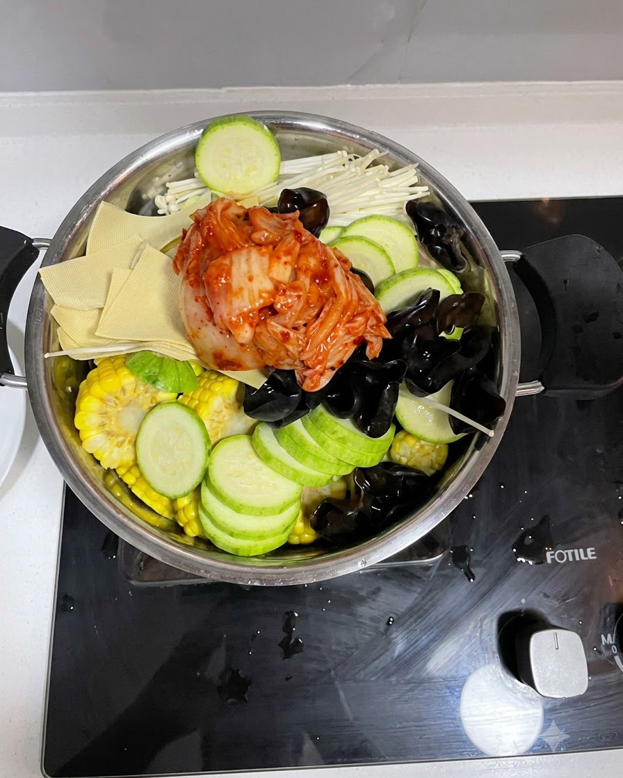 Die vorbereitete Sauce wird über die Zutaten im Kochtopf gegossen.
