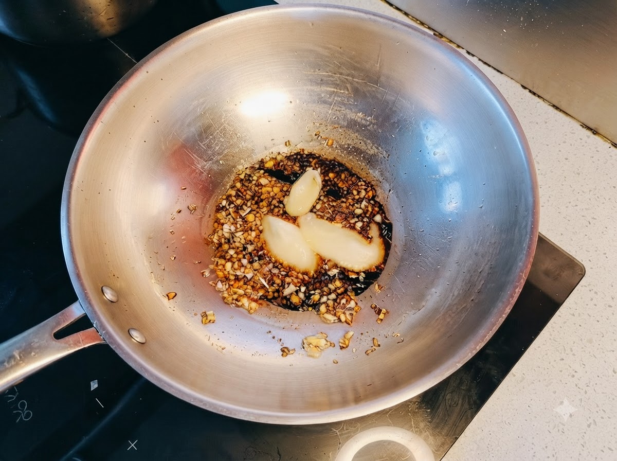 Mehr gehackter Knoblauch wird zur blubbernden Sauce im Wok gegeben.