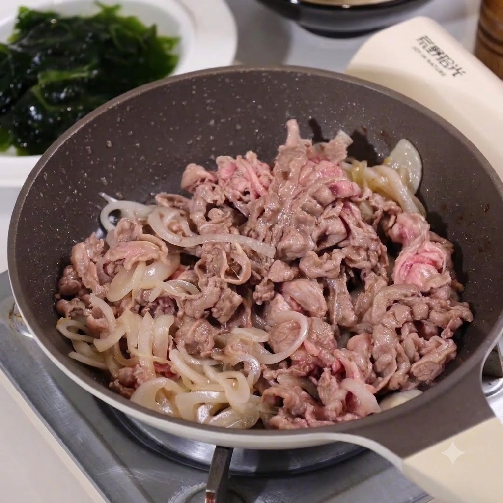 Rindfleisch und Zwiebeln kochen zusammen in einer Pfanne und nehmen Säfte auf.