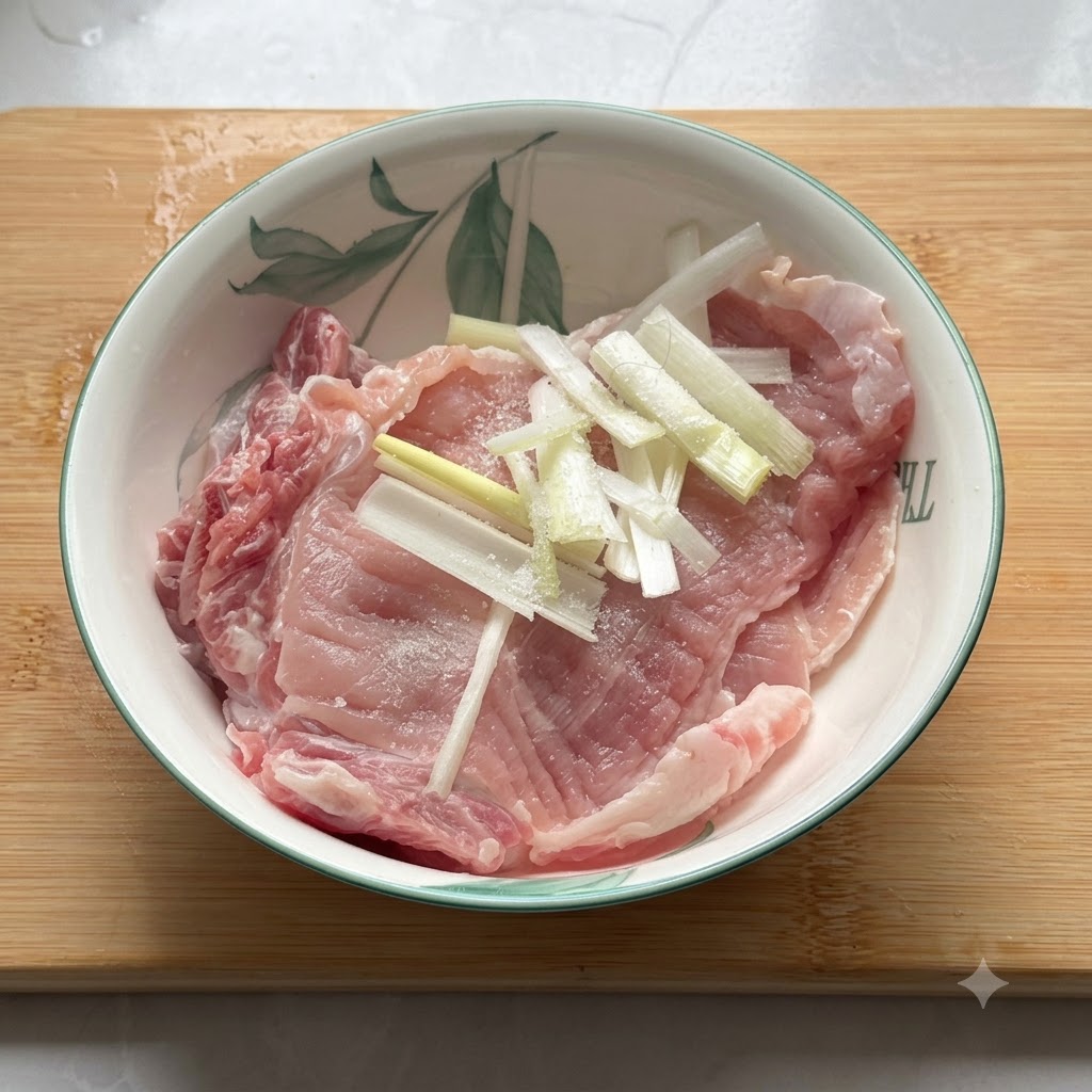 Rohes Schweinekotelett in einer Keramikschüssel, gewürzt mit Salz, Pfeffer und Frühlingszwiebelstücken.