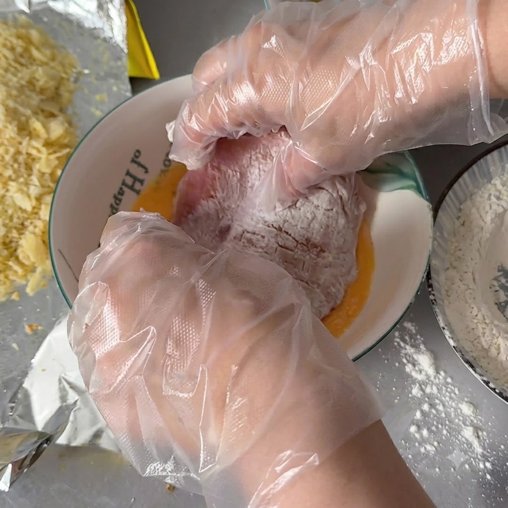 Behandschuhte Hände tauchen ein mit Mehl bestäubtes Schweinekotelett in eine Schüssel mit verquirlten Eiern.