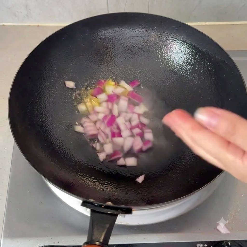 Gewürfelte rote Zwiebeln brutzeln in einem schwarzen Wok mit heißem Öl.