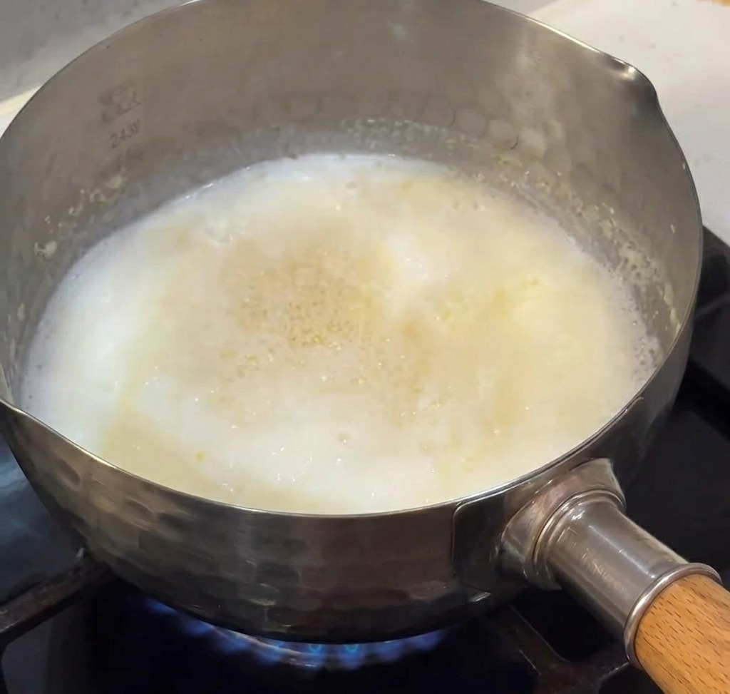 Milch und Käse schmelzen in einem Topf auf dem Herd, um eine glatte Käsesauce zu bilden.
