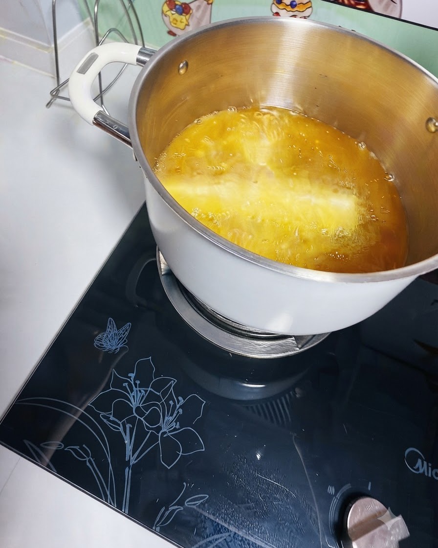 Kartoffelstreifen frittieren in einem tiefen Metalltopf mit heißem Öl auf einem Induktionsherd.