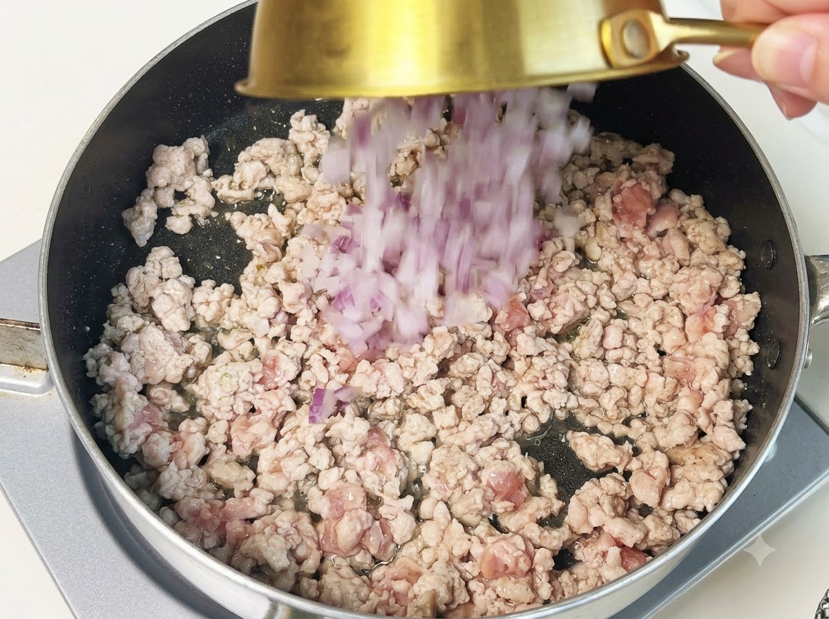 Gehackte lila Zwiebeln werden in eine Pfanne mit angebratenem Hackfleisch gegeben.