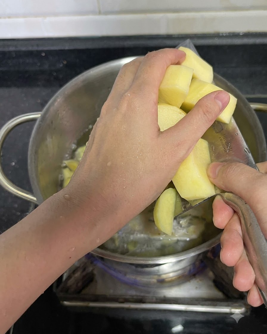 Eine Hand schüttet geschnittene Kartoffelstücke in den Kochtopf.