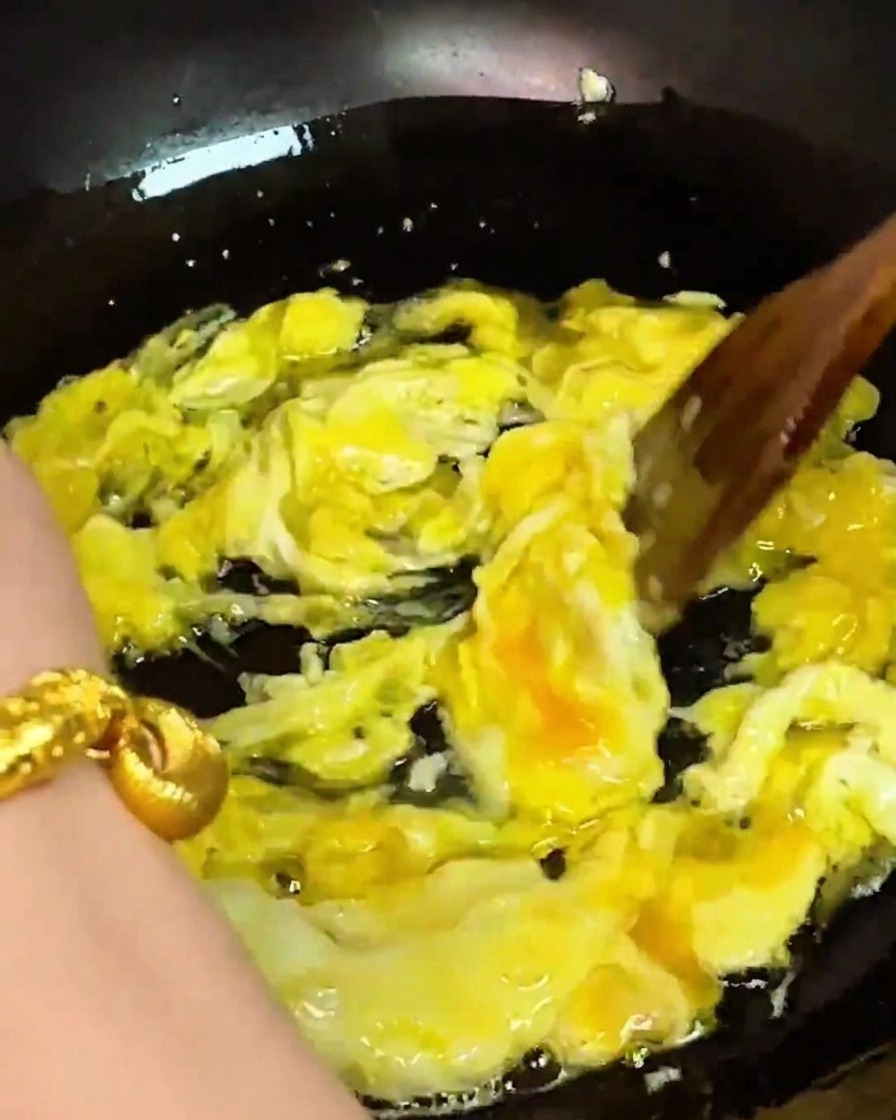 Rührei wird in einem Wok gerührt, während frisches Schwimmkrabbenfleisch hinzugefügt wird.